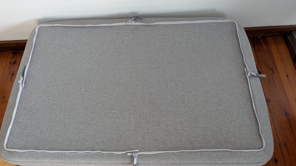 A top-down view of the standalone rectangular grey fabric base of an Omlet Topology dog bed resting on polished timber flooring, showcasing the heavy-duty perimeter zipper track used to attach interchangeable toppers.