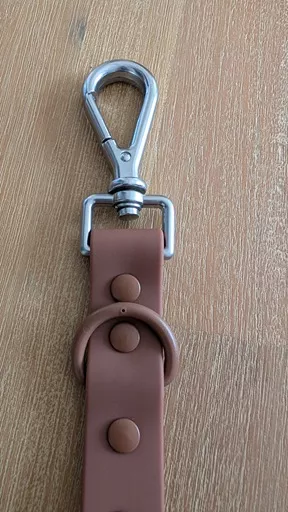 Close up shot of the silver metal swivel snap clip, D-ring, and colour-matched rivets on The Furry Nomad Chocolate Brown waterproof leash.
