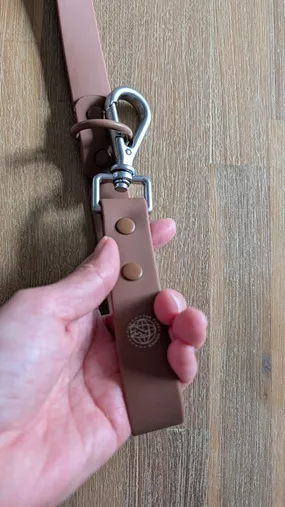 Close up of hand holding Chocolate Brown waterproof leash handle showing heavy metal swivel clip and D-ring from The Furry Nomad.