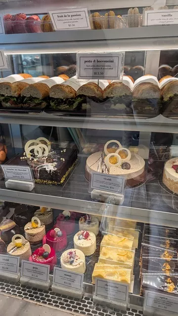 A bakery display case filled with gourmet baguettes, macarons, and artisanal gateaux at La Renaissance Patisserie.
