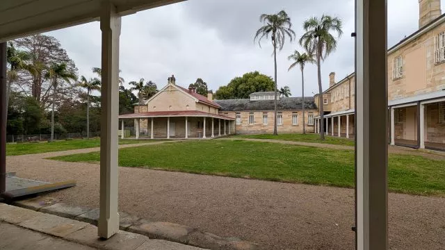 View of the inner courtyard and heritage buildings framed by the covered veranda pillars at Havenstone Cafe.