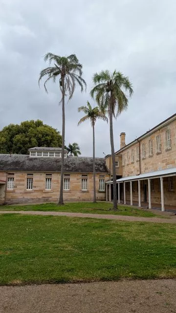 Historic sandstone buildings and tall palm trees in the inner courtyard of Havenstone Cafe at the Parramatta Female Factory precinct.
