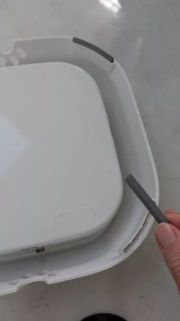 A hand holding up one of the small detachable grey rubber feet from the bottom base of the All Fur You dog water bowl.