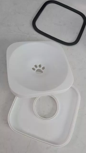 The disassembled parts of the All Fur You water bowl floating plate, showing the two unsealed halves separated alongside the black outer rim.