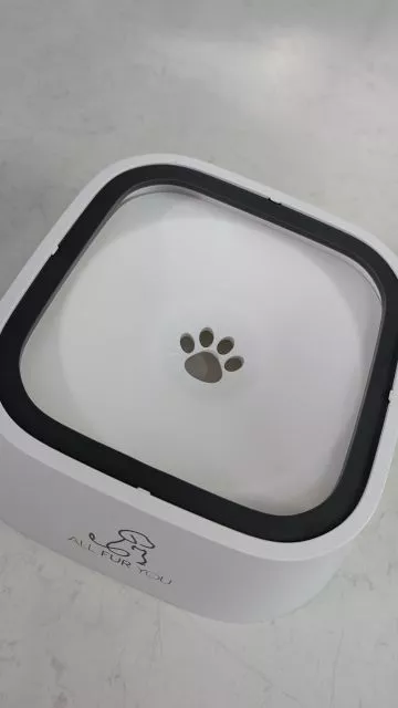 A top-down view of the white and grey All Fur You floating plate water bowl, highlighting its clean aesthetic and central paw-shaped water drainage opening.