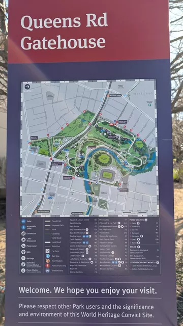 Close-up of an informational signboard titled Queens Rd Gatehouse featuring a detailed illustrated map of Parramatta Park, walking trails, and landmark directories.